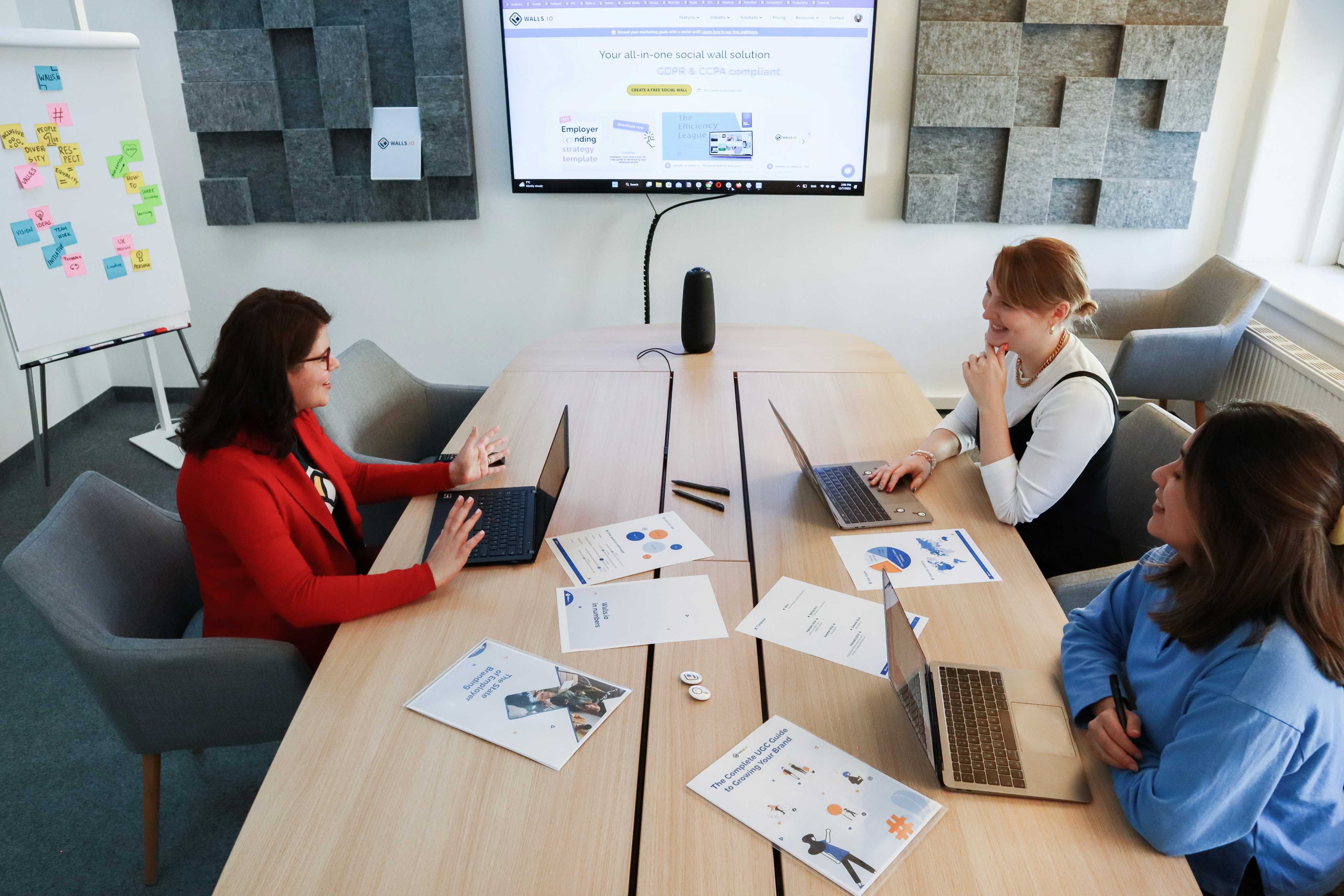 Equipe reunida em uma mesa de trabalho com notebooks e relatórios
